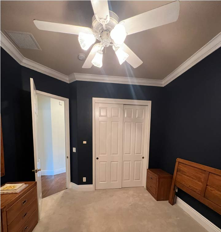 Modern master bedroom interior painting featuring deep navy blue accent walls and crisp white crown molding