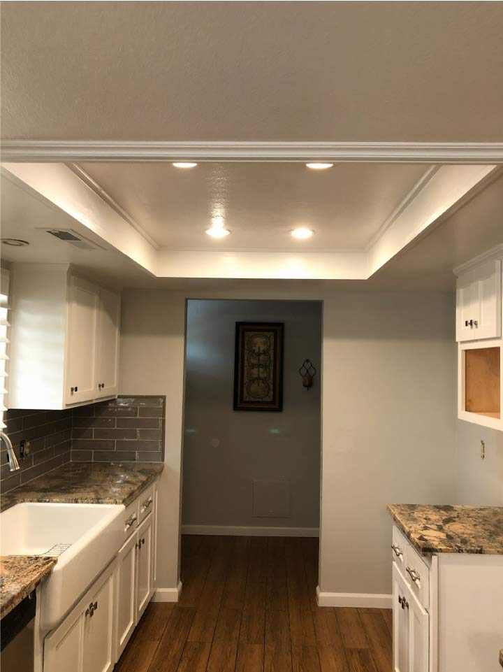 Refinished white kitchen cabinets and soft gray walls in a modern residential apartment renovation