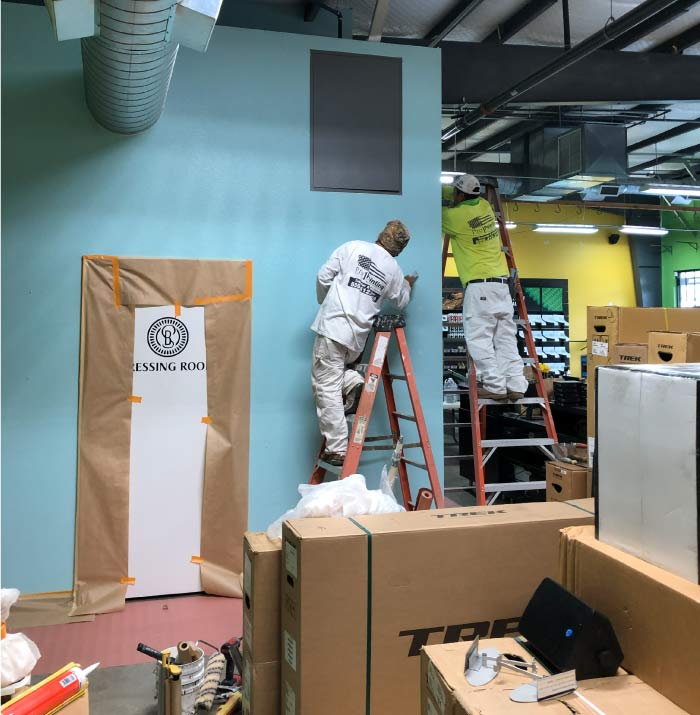 Pro 1 Painting uniformed crew on ladders painting high walls in a large commercial retail warehouse