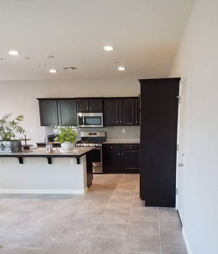 Open concept residential interior painting with light grey walls and white trim connecting the living room and kitchen areas.